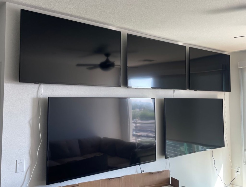 Five large TVs mounted level across a wall